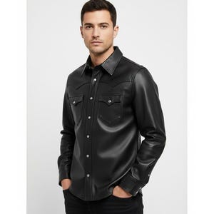 May include: Black leather shirt with a classic collar, two chest pockets, and silver-tone button closures. The long-sleeved shirt has a Western-style yoke detail and is worn with black jeans. A modern take on a timeless style.