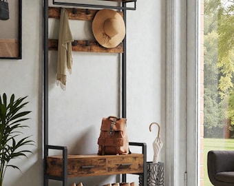May include: A black metal and wood entryway organizer with a bench, shoe rack, and coat rack. A tan hat, scarf, and backpack are displayed on the rack. Shoes are neatly arranged on the shoe rack. The organizer is against a white wall.