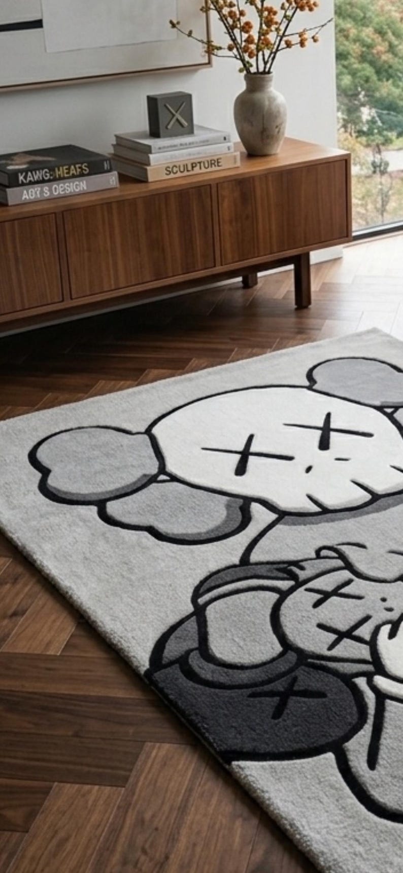 Pu&ograve; includere: Un tappeto rettangolare raffigurante un grande personaggio dei cartoni animati stilizzato con una testa simile a un teschio, orecchie rotonde e occhi a forma di X. Il design &egrave; realizzato in tonalit&agrave; grigio chiaro, grigio scuro e bianco.