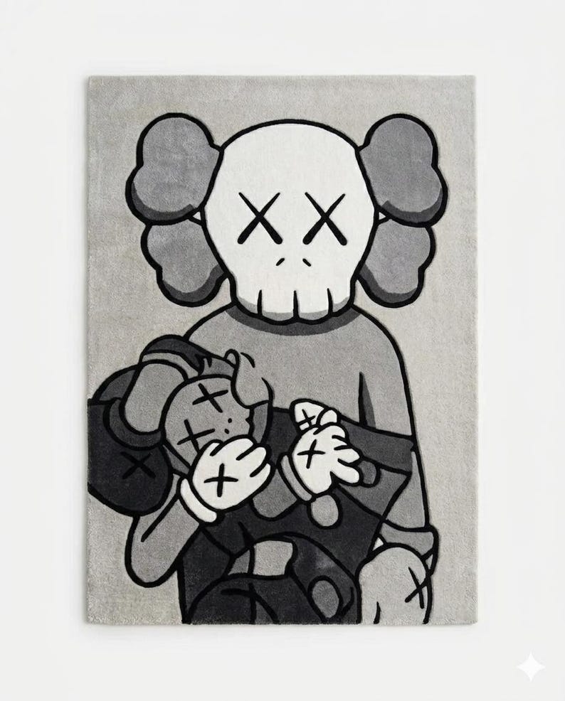 Pu&ograve; includere: Un tappeto rettangolare con un'illustrazione grafica monocromatica in grigio, nero e bianco di un personaggio dei cartoni animati con occhi a forma di X che tiene in braccio una figura pi&ugrave; piccola. Il design usa contorni neri e toni di grigio.