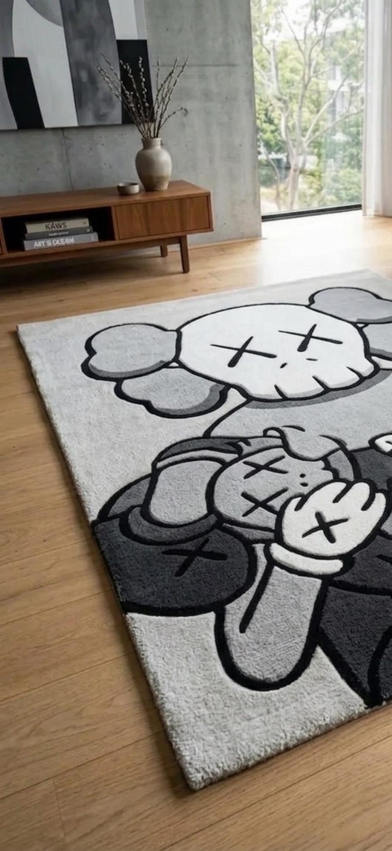 Pu&ograve; includere: Un tappeto rettangolare con una grande illustrazione grafica in grigio e bianco di un personaggio dei cartoni animati con occhi a forma di X e mani guantate. Il design include una testa simile a un teschio e una figura con le mani sul viso.