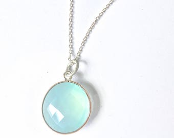 May include: A silver chain necklace with a light blue gemstone pendant. The pendant is round and has a faceted design.