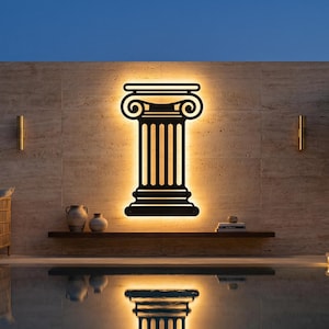 May include: A black, illuminated pillar design mounted on a textured wall, reflecting in a pool of water. The architectural element is lit from behind, creating a warm glow. The scene includes a seating area, decorative vases, and a potted tree.