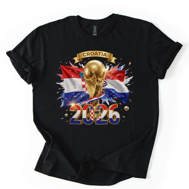 Może przedstawiać: Czarny t-shirt z graficznym wzorem przedstawiającym chorwacką flagę, złoty puchar i napis "CROATIA 2026". Projekt zawiera złote konfetti i transparent.