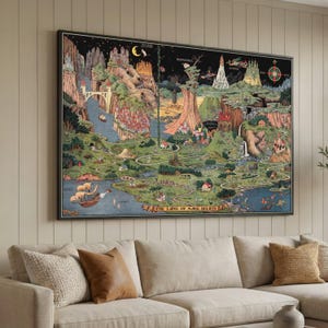 May include: A framed, colourful map titled "THE LAND OF MAKE BELIEVE" depicts a whimsical landscape with castles, mountains, and waterways. The map features a black border and is displayed above a beige sofa with decorative cushions.