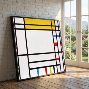 Op de afbeelding: Een ingelijste kunstdruk met een geometrisch ontwerp. Het kunstwerk toont zwarte lijnen en kleurvlakken, waaronder gele, rode en blauwe rechthoeken op een witte achtergrond. Het zwarte frame leunt tegen een witte bakstenen muur.