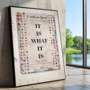 May include: Framed artwork with the text "IT IS WHAT IT IS" in large black letters. The artwork has a distressed, vintage look with colorful polka dots and the text "A McQueen Special". The frame is black.