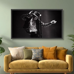May include: Monochrome framed print of a performer in a fedora and sequined jacket, holding a microphone on stage. The print hangs above a yellow sofa with assorted cushions.