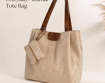 Puede incluir: Bolso tote de lona beige con asas y detalles en cuero marrón. Incluye una pequeña bolsa con cremallera a juego. El texto "Everyday Minimal Tote Bag" está impreso en la esquina superior izquierda. El bolso tiene un diseño minimalista.