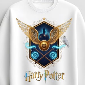 Może przedstawiać: Biała bluza z kapturem z szczegółową grafiką przedstawiającą złoty znicz, różdżki i śnieżną sowę. Projekt zawiera sylwetkę zamku i napis "Harry Potter". Grafika jest szczegółowa i kolorowa.