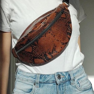 Op de afbeelding: Een set van drie keramische mokken met een gespikkelde, crèmekleurige glazuur. Elke mok heeft een handgeschilderd bloemmotief in blauw, groen en geel. De mokken hebben een eenvoudige, afgeronde vorm.