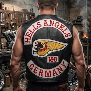 May include: Black leather vest with the words "HELLS ANGELS" in red lettering. A patch featuring a skull with wings and the letters "MG" is also visible. The word "GERMANY" is displayed in red on the bottom of the vest.