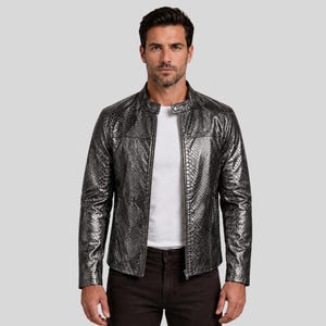 May include: A silver and black faux snakeskin jacket with a stand-up collar and a zipper closure. The jacket is worn over a white t-shirt and dark brown pants. The jacket has a textured appearance.