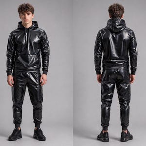 May include: A two-piece black outfit featuring a hooded sweatshirt and matching pants. The shiny material reflects light, creating a glossy appearance. The sweatshirt has a front pocket and the pants have a tapered fit.
