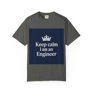Könnte beinhalten: Dunkelgraues T-Shirt mit einem marineblauen Rechteck auf der Vorderseite. Das Rechteck zeigt eine weiße Krone über dem Text "Keep calm I am an Engineer" in weißer, serifenloser Schrift. Das T-Shirt hat kurze Ärmel und einen Rundhalsausschnitt.