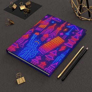 Può includere: Un diario con copertina rigida con un vivace design del skyline urbano al neon nei toni del blu, rosa, arancione e viola. La copertina presenta monumenti iconici. Graffette e matite dorate sono disposte attorno al diario.