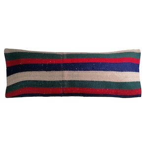 Könnte beinhalten: Ein langes, rechteckiges Kissen mit horizontalen Streifen in Rot, Grün, Blau und Beige. Das Kissen besteht aus einem gewebten Stoff, wobei die Streifen gleichmäßig über die Oberfläche verteilt sind.
