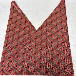 May include: A red and black patterned fabric, cut into a V-shape. The fabric features a repeating geometric design of squares within squares, creating a textured appearance. The color palette includes shades of red, black, and gold.
