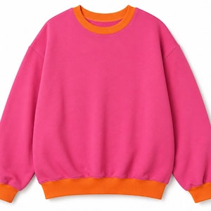 Könnte beinhalten: Ein leuchtend pinkfarbenes Sweatshirt mit orangefarbenen Details an Kragen, Bündchen und Saum. Das langärmlige Oberteil hat einen Rundhalsausschnitt und eine lockere Passform. Die leuchtende Farbkombination erzeugt einen auffälligen Look. Dieses lässige Kleidungsstück ist für den Alltag geeignet.