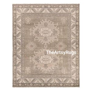 May include: A rectangular area rug with a central medallion design in shades of gray and beige. The rug features an intricate border and a repeating pattern. The text "TheArtsyRugs" is visible on the rug.