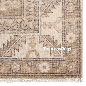 May include: Close-up of a beige and brown patterned rug with a fringe. The rug features geometric designs and the text "TheArtsyRugs". The rug has a vintage, distressed look.