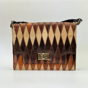 Könnte beinhalten: Eine rechteckige Handtasche mit einem geometrischen Rautenmuster in Braun-, Beige- und Orangetönen. Die Tasche hat einen goldfarbenen Verschluss und einen schwarzen Griff. Das Design ähnelt Schlangenhaut.