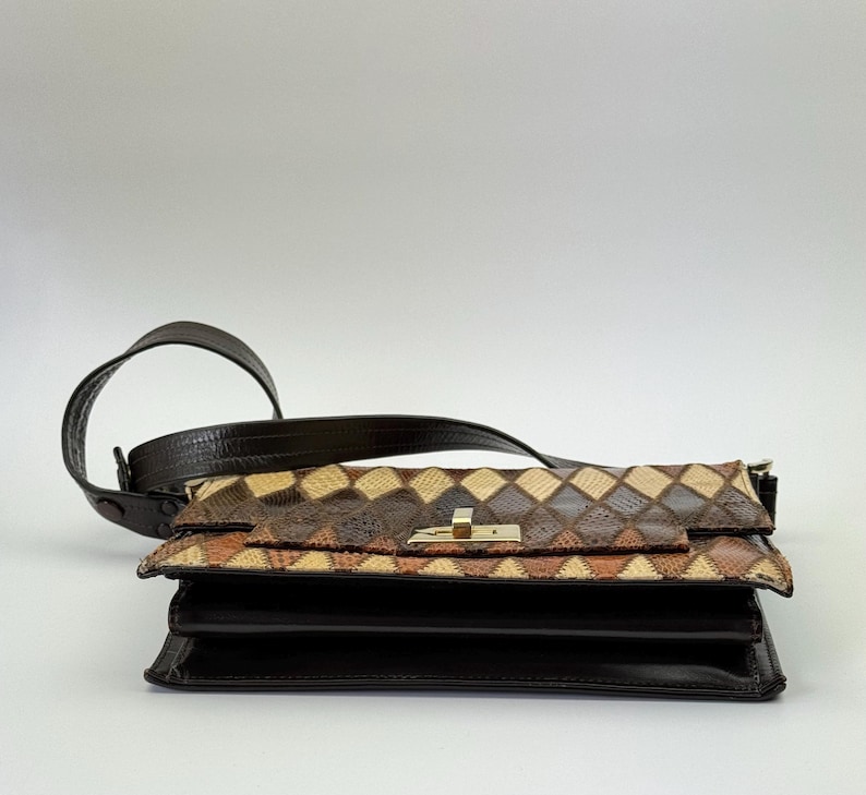 May include: A brown leather shoulder bag with a geometric pattern on the flap. The bag has a dark brown strap and a gold-colored clasp. The body of the bag is a solid dark brown.