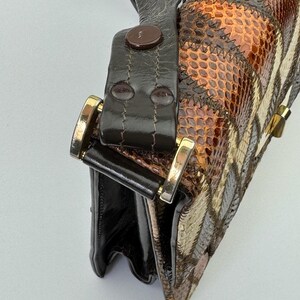 May include: A vintage handbag with a patchwork design. The bag features a mix of brown, tan, and cream-colored panels with a snakeskin pattern. It has a dark brown leather strap and gold-colored hardware.