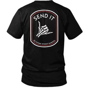May include: Black t-shirt featuring a white and red emblem with the words "SEND IT" above a skeleton hand making a shaka sign. The emblem also includes the text "NO VICTORY WITHOUT SACRIFICE".