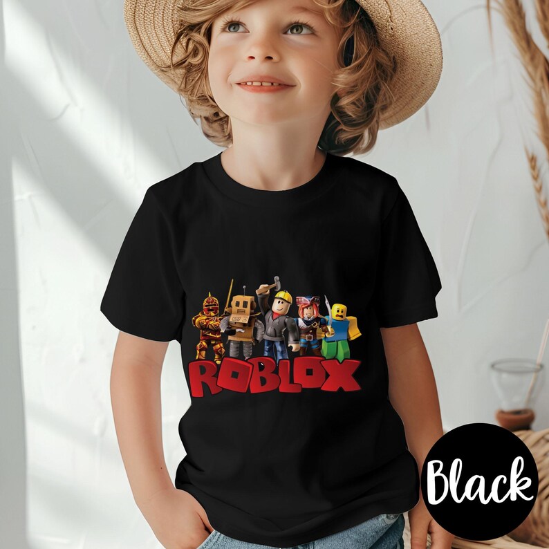 May include: Black short-sleeved t-shirt featuring a colorful graphic of Roblox characters and the Roblox logo in red. The shirt is worn by a child. A black circle with the word "Black" is in the lower right corner.
