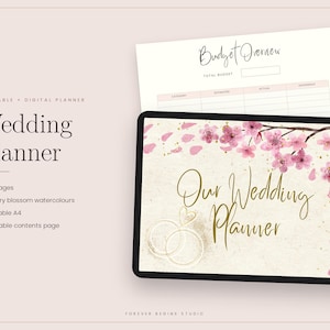 Könnte beinhalten: Ein digitaler Hochzeitsplaner auf einem Tablet-Bildschirm mit einem Cover, das den goldenen Schriftzug Our Wedding Planner und rosa Kirschblüten-Aquarellillustrationen zeigt. Eine Budgetübersicht ist hinter dem Tablet zu sehen.