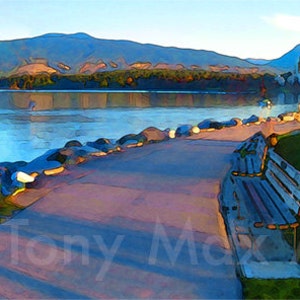 May include: A panoramic view of a city skyline with a waterfront park. The park has a grassy area with a bench, a paved path, and a rocky shoreline. The city skyline is in the background, with tall buildings and mountains. The sky is blue and the water is calm.