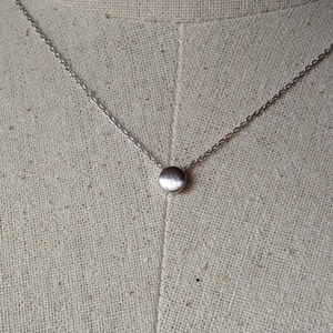 May include: A silver chain necklace with a small, round pendant.