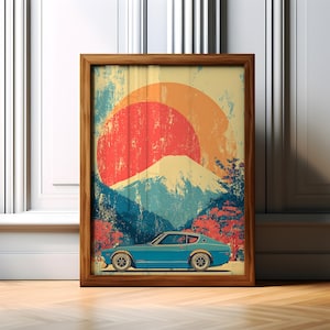 May include: A framed art print featuring a vintage car in teal, set against a backdrop of a mountain and a rising sun in shades of red, orange, and yellow. The artwork has a distressed, vintage aesthetic, with a wooden frame.