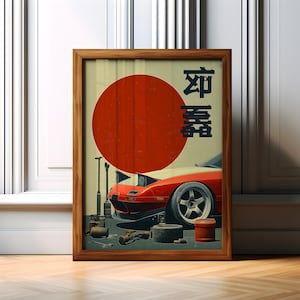 May include: A framed print depicting a red and white sports car with a large red circle and Japanese characters. The artwork, in a wooden frame, includes tools and a tyre, evoking a car repair theme. The print is displayed on a wooden floor.