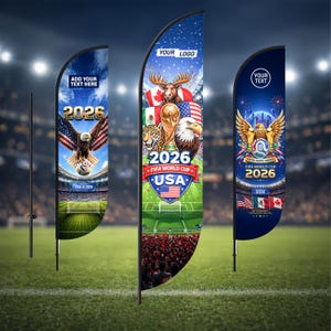 May include: Three feather flags with soccer-themed designs. The flags feature the text "2026" and "FIFA WORLD CUP USA". One flag has an eagle, another has a trophy and a jaguar, and the third has an eagle with a cityscape. The flags are on a green field.