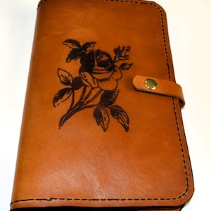 Capa para diário A5 feita à mão em couro rosa gravado. Vem com 1 diário pautado A5 instalado. Dois suportes para caneta e dois bolsos para cartão.