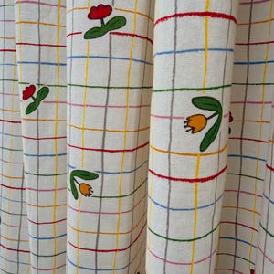 May include: A trio of cream-glazed ceramic mugs with a speckled finish. Each mug is adorned with a hand-painted design: a blue and green leaf, a yellow flower, and a red berry. The mugs have a simple, rounded form.