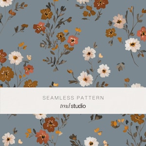 May include: A seamless pattern featuring a dusty blue background with scattered hand-painted style flowers in shades of white, burnt orange, and brown. A white horizontal band across the center displays the text SEAMLESS PATTERN trnd studio.