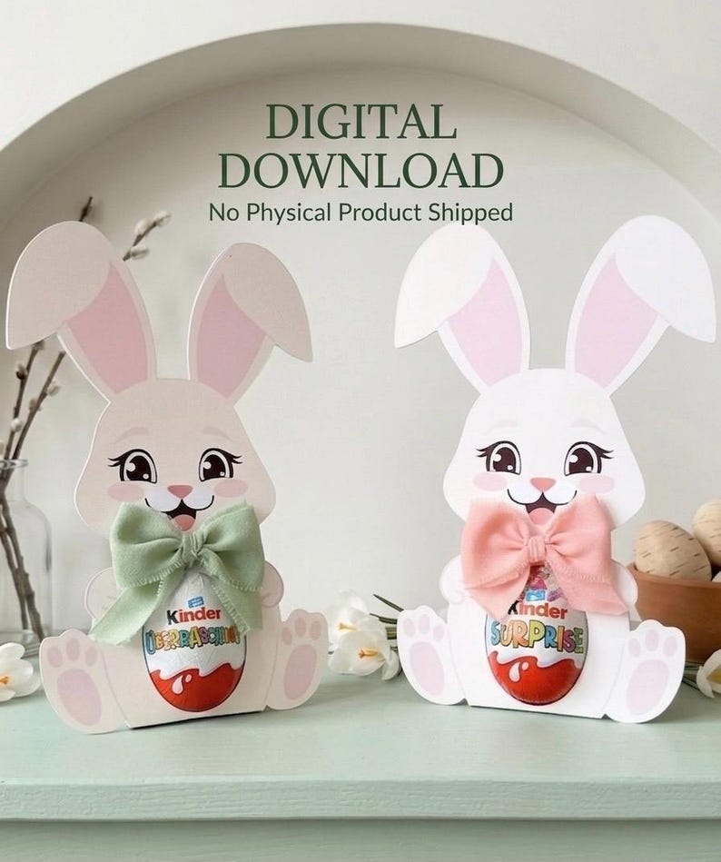 Two cute paper Easter bunny Kinder egg holders in pink and white, wearing green and pink fabric bows, standing on a light green surface with decorative willow branches and mini Easter eggs in the background