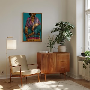 May include: A framed wall art print depicting a person wearing a pink and blue striped shirt, teal trousers, and gold jewelry, sitting on a stack of books. The artwork features a vibrant teal background and is displayed in a wooden frame.
