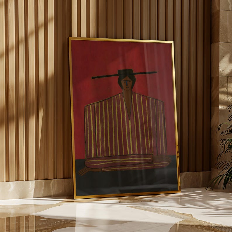 May include: A framed wall art print featuring a stylized figure wearing a wide-brimmed hat and a striped garment with yellow and red vertical lines. The figure is set against a deep red background with a dark horizontal base, all encased in a gold frame.