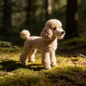 May include: A beige poodle ornament, crafted from wool, stands on moss in a woodland scene. The dog has a distinctive curly coat and a small, fluffy tail. The background is blurred, with sunlight filtering through the trees.