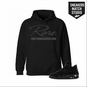 Puede incluir: Sudadera con capucha negra con la palabra "Rare" en fuente cursiva, con "AIR" debajo. Un par de zapatillas negras está al lado de la sudadera con capucha. Las zapatillas son negras con suela negra. El texto "Sneakers Match Studio" está en la esquina superior derecha.