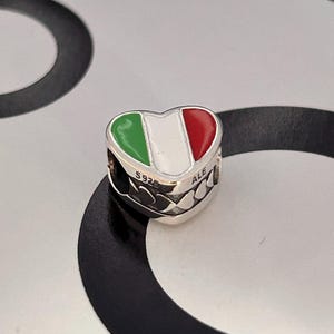 以下が含まれることがあります： イタリアの国旗のデザインが施されたハート型のチャーム。チャームは緑、白、赤のエナメルを使用しています。チャームはシルバー製で、「S925」と「ALE」の刻印があります。