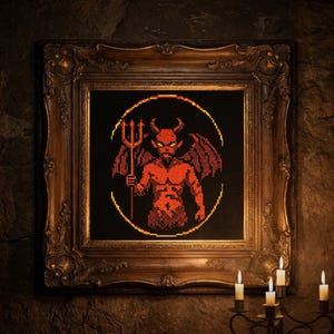 May include: A framed cross-stitch artwork featuring a red devil holding a trident, set against a black background. The artwork is in a gold ornate frame. Lit candles are in the foreground, creating a gothic aesthetic.