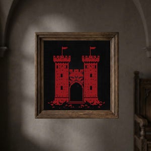 May include: A framed cross-stitch artwork featuring a red castle design against a black background. The castle has two towers with small red flags, a central gate, and a detailed facade. The frame is made of wood.