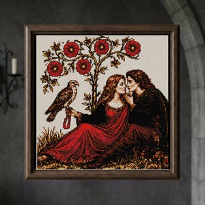 May include: Framed cross-stitch artwork depicting a romantic scene. A couple in medieval attire is under a tree with red flowers. A falcon perches on a person's arm. The artwork is in a wooden frame.