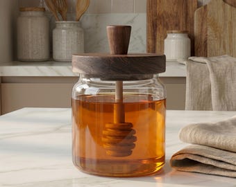 May include: A clear glass honey jar with a wooden lid and dipper. The jar is filled with golden honey. The wooden lid and dipper have a dark brown finish. Kitchenware and food storage.