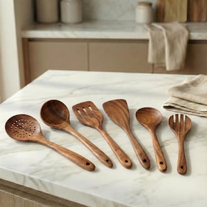 Könnte beinhalten: Ein Set aus sechs hölzernen Küchenutensilien, darunter ein Schöpflöffel, ein normaler Löffel, ein geschlitzter Pfannenwender, ein normaler Pfannenwender, ein Löffel und eine Gabel. Die Utensilien sind aus hellbraunem Holz gefertigt.